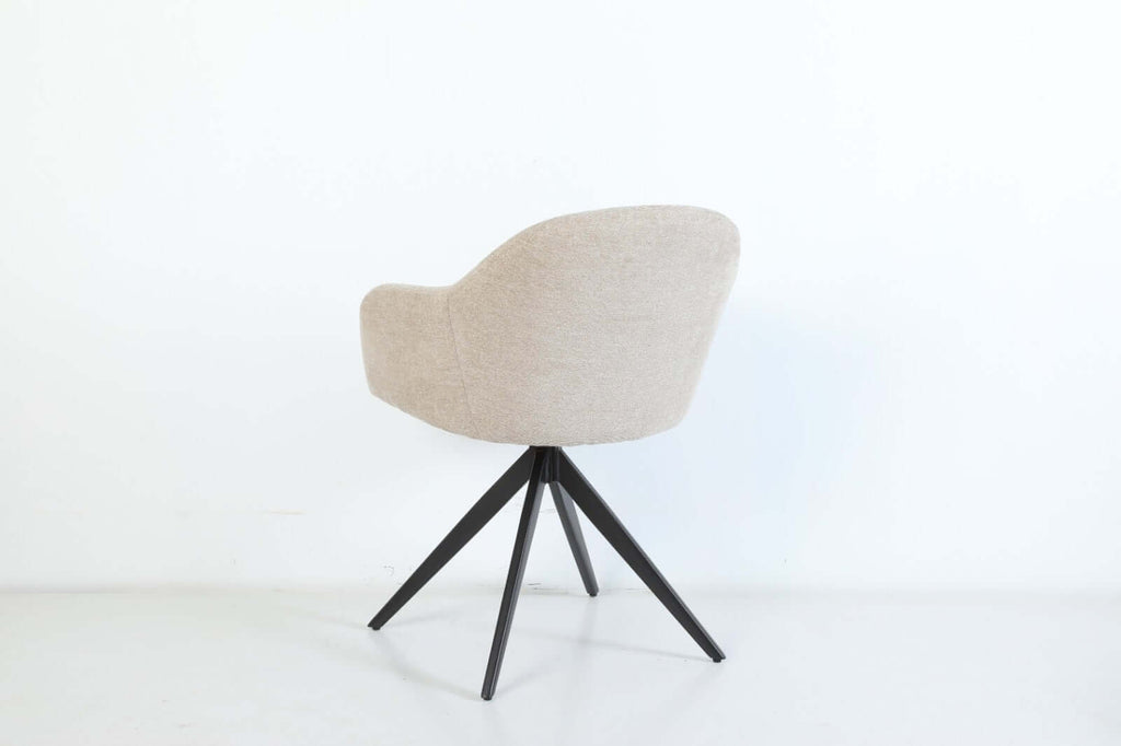 De Maxim eetkamerstoel van VSO Design combineert minimalistische elegantie met optimaal zitcomfort. De zachte, neutraal gekleurde stoffering sluit naadloos aan bij diverse interieurstijlen, van Scandinavisch tot modern industrieel. De volledig gesloten kuipvorm met geïntegreerde armleuningen zorgt voor een comfortabele en ondersteunende zitervaring.

Het robuuste zwarte metalen onderstel met vier taps toelopende poten in kruisvorm geeft de Maxim een stabiele basis en een subtiele design-touch.