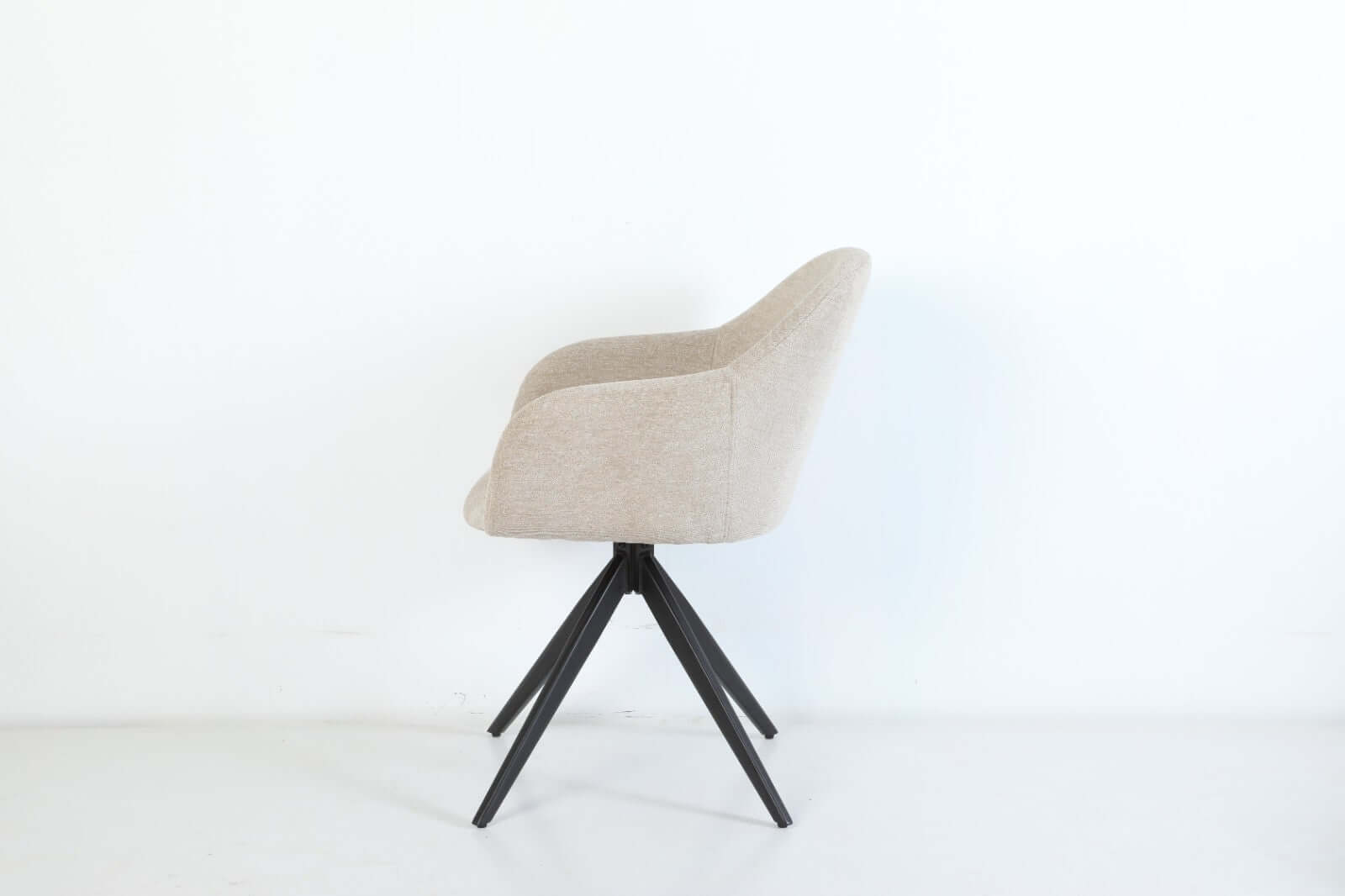 De Maxim eetkamerstoel van VSO Design combineert minimalistische elegantie met optimaal zitcomfort. De zachte, neutraal gekleurde stoffering sluit naadloos aan bij diverse interieurstijlen, van Scandinavisch tot modern industrieel. De volledig gesloten kuipvorm met geïntegreerde armleuningen zorgt voor een comfortabele en ondersteunende zitervaring.

Het robuuste zwarte metalen onderstel met vier taps toelopende poten in kruisvorm geeft de Maxim een stabiele basis en een subtiele design-touch.